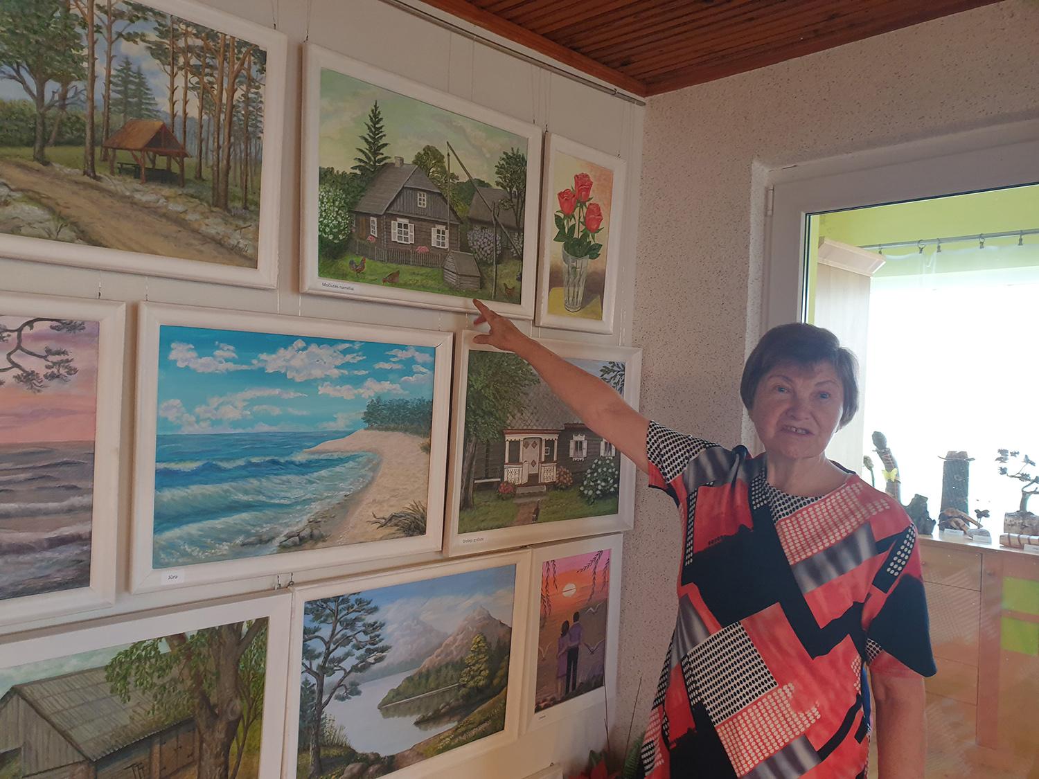 „Kartu su medžiais čia giliai įleidau savo šaknis“ / Asmeninio archyvo nuotr. A. Stancikienė prie savo paveikslų.