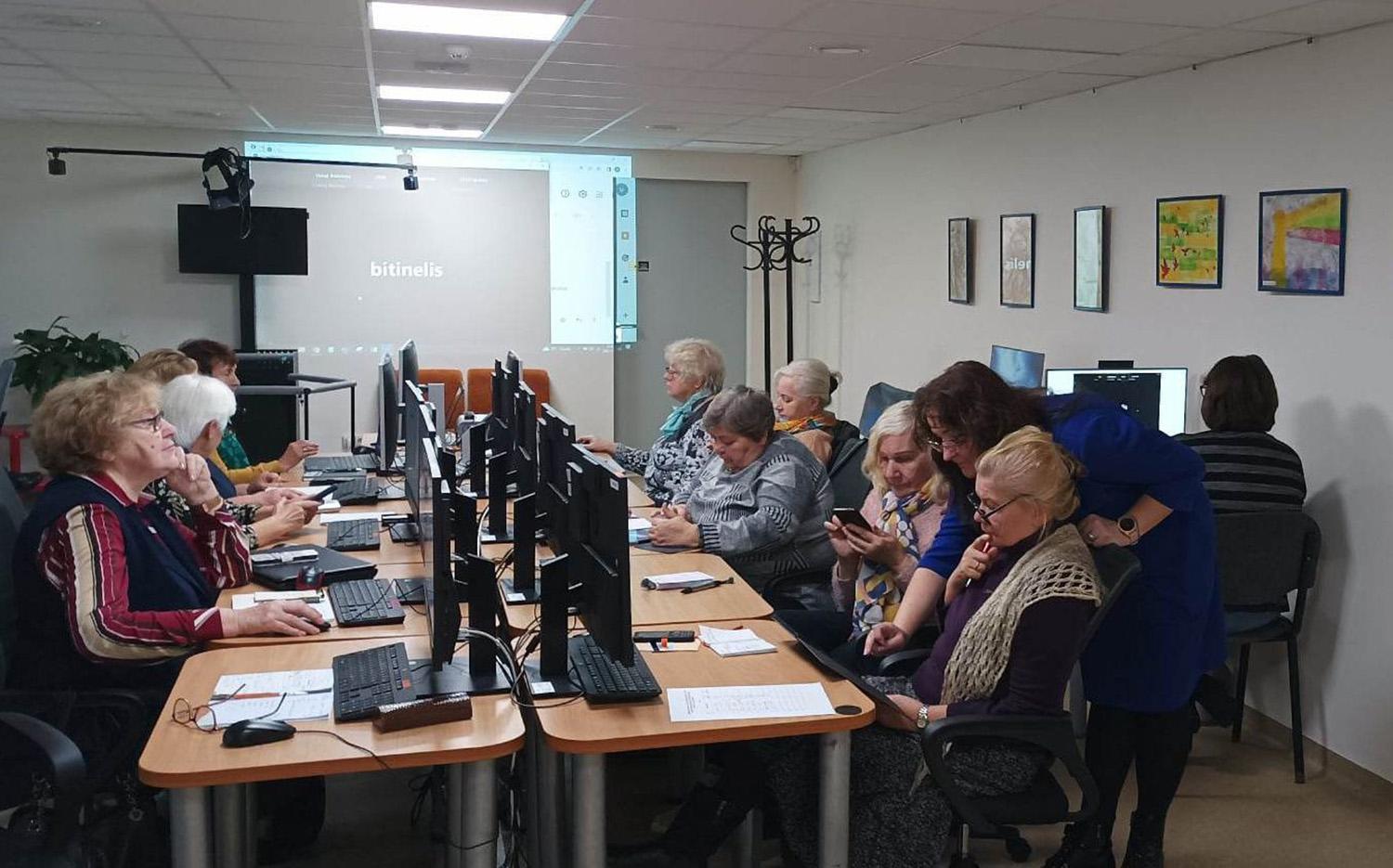 Kompiuterinių įgūdžių mokosi senjorai / Senjorės tobulina kompiuterinio raštingumo įgūdžius.